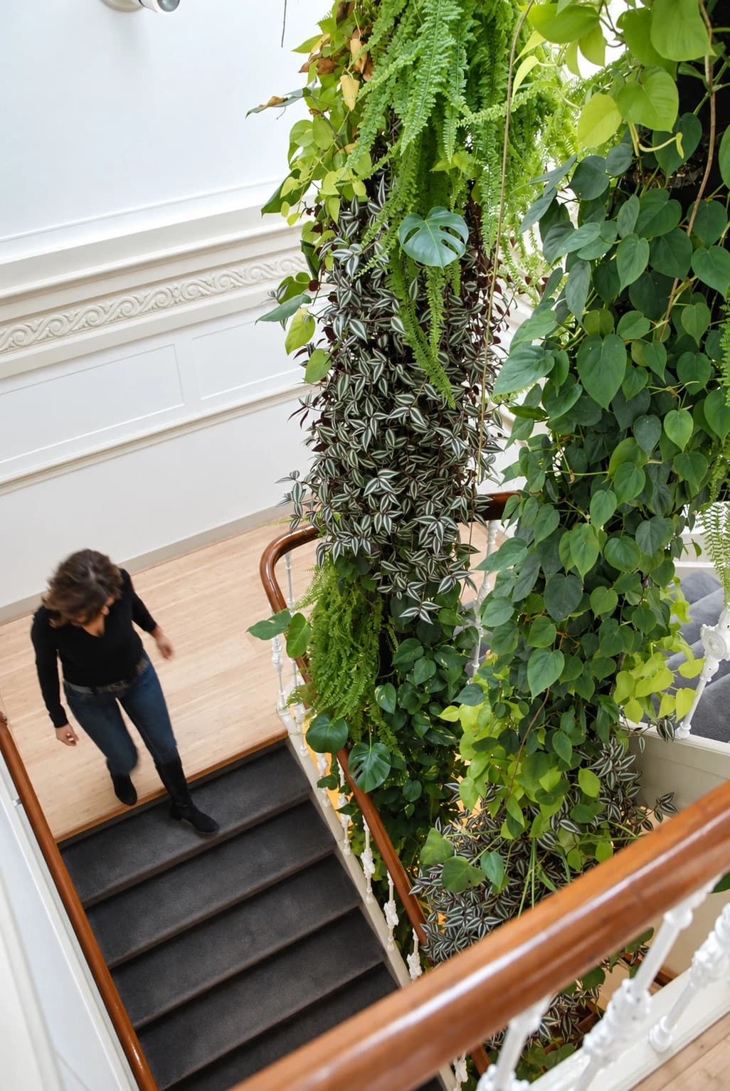 Person climbing the staircase beside cascading indoor plants at the Center for Applied Games.